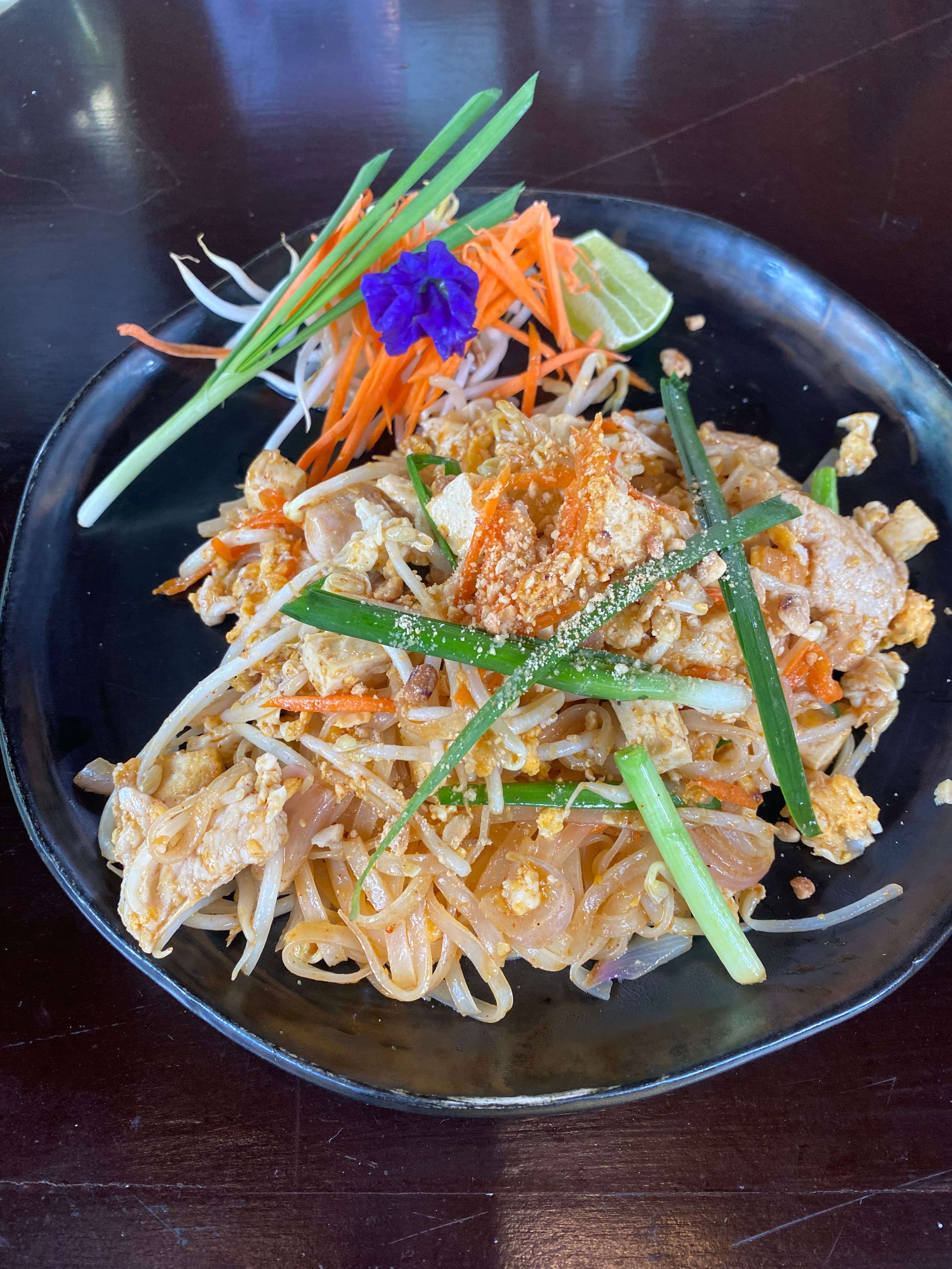 A plate of pad thai and fresh toppings at a market stall