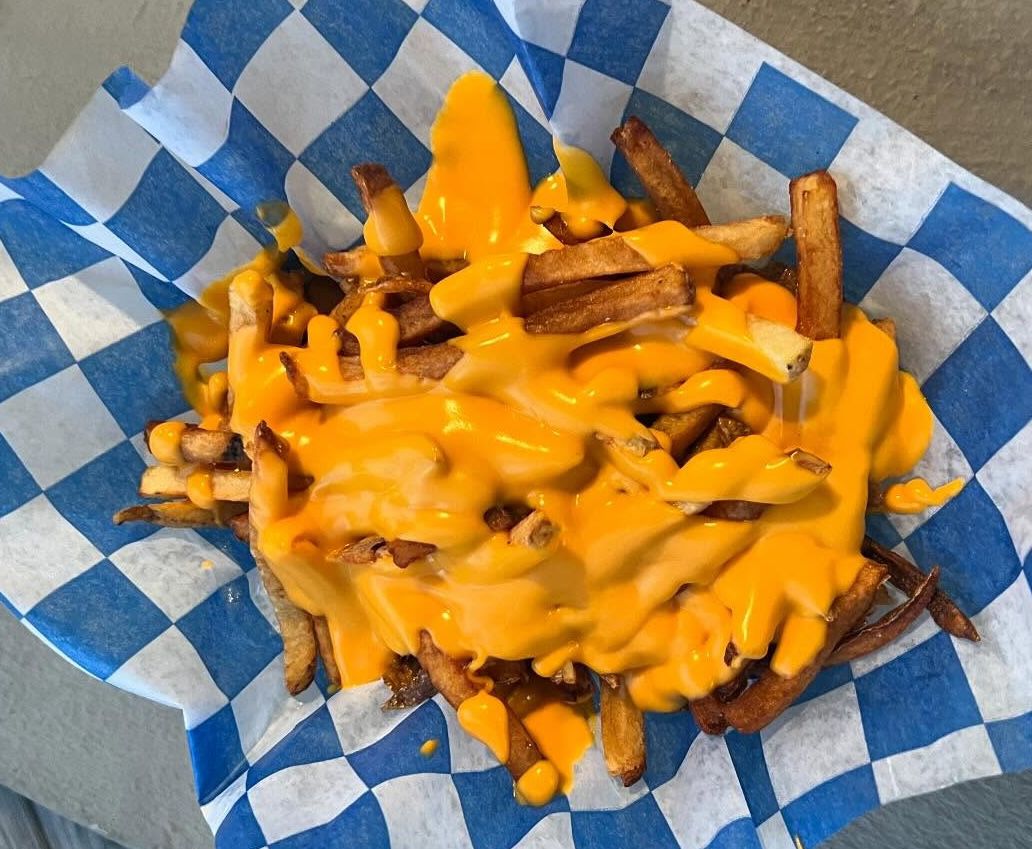 Jersey Shore boardwalk fries topped with bright orange cheese sauce in a blue-and-white paper tray