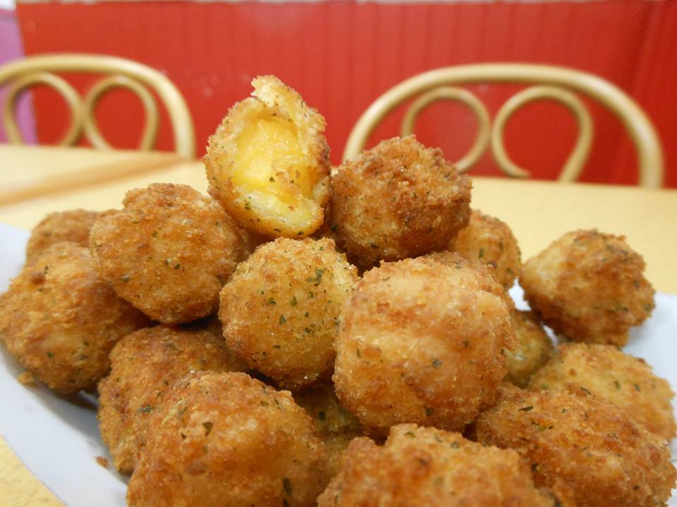 Plate of golden fried cheese balls with one broken open to show melted cheese inside