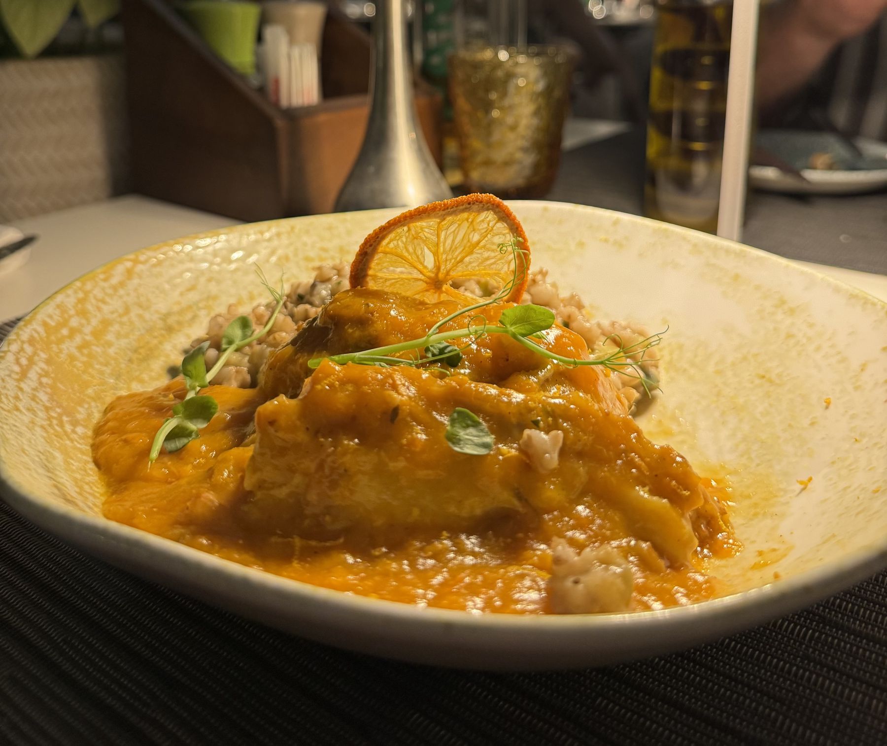 Capon plated with orange-toned sauce and grains in Dubrovnik
