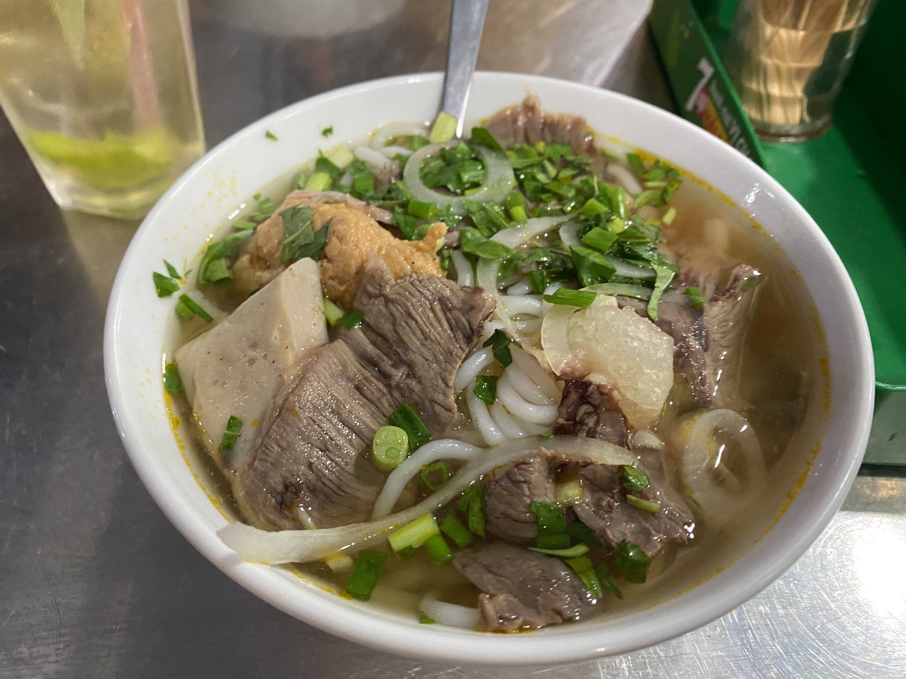 Bowl of pho bo with beef, rice noodles, onions, and herbs