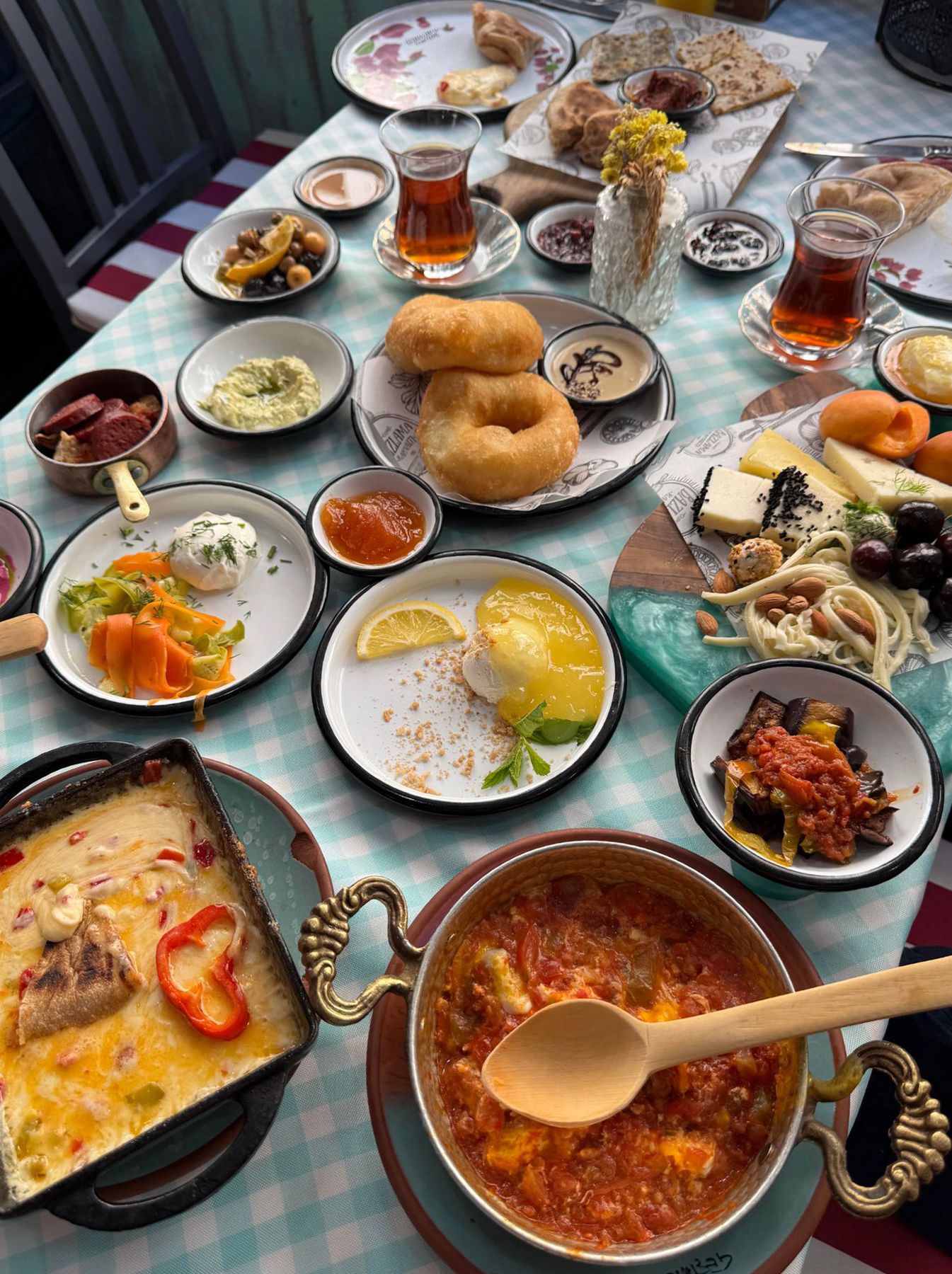 Overhead view of a Turkish breakfast spread with cheese, borek, menemen, and tea