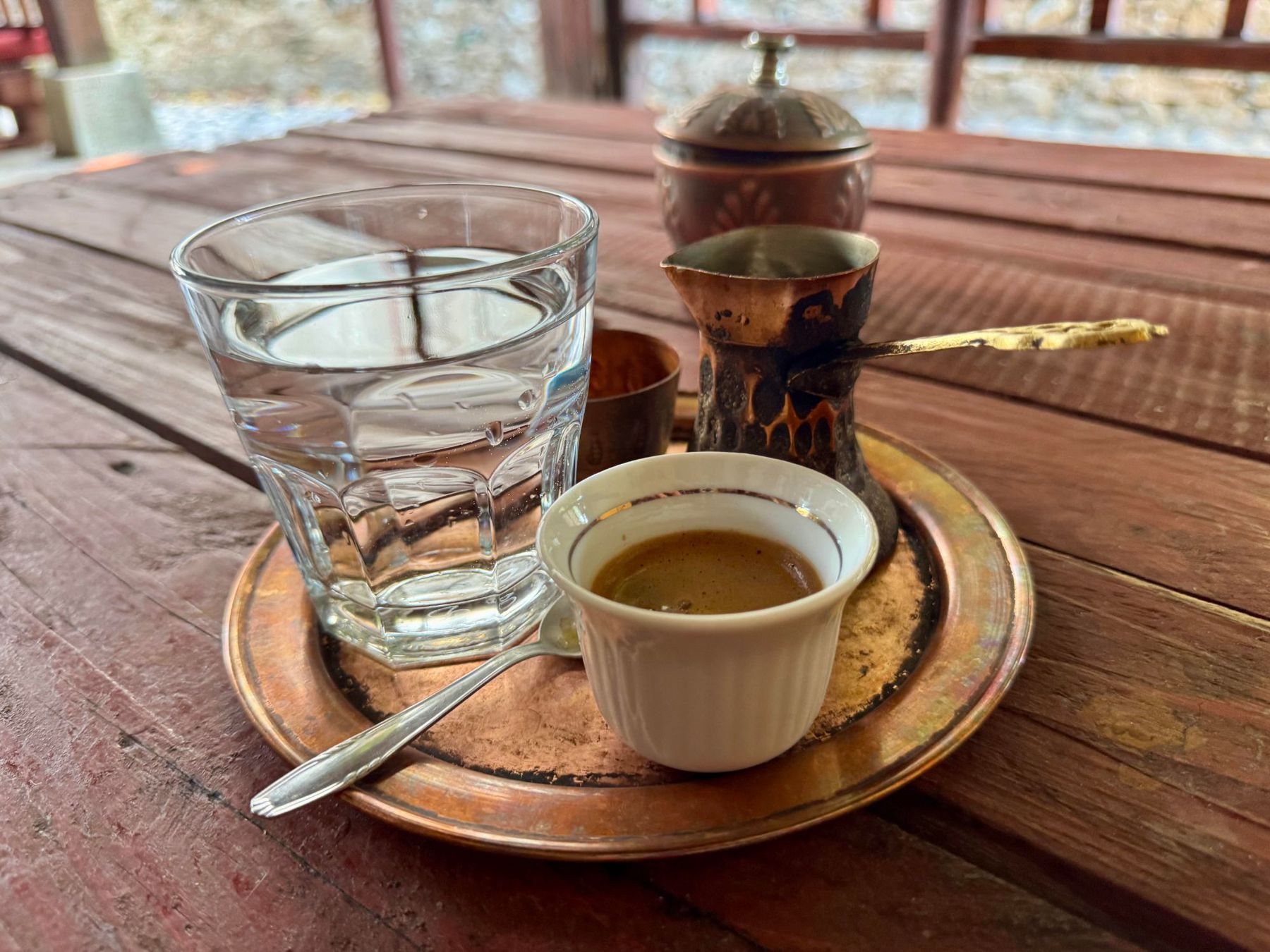 Turkish coffee served with water and copper cezve on a wooden table