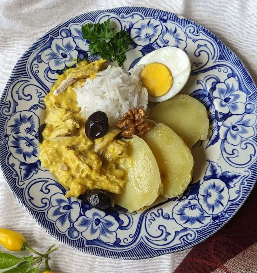 Aji de gallina served with rice and potatoes in Lima