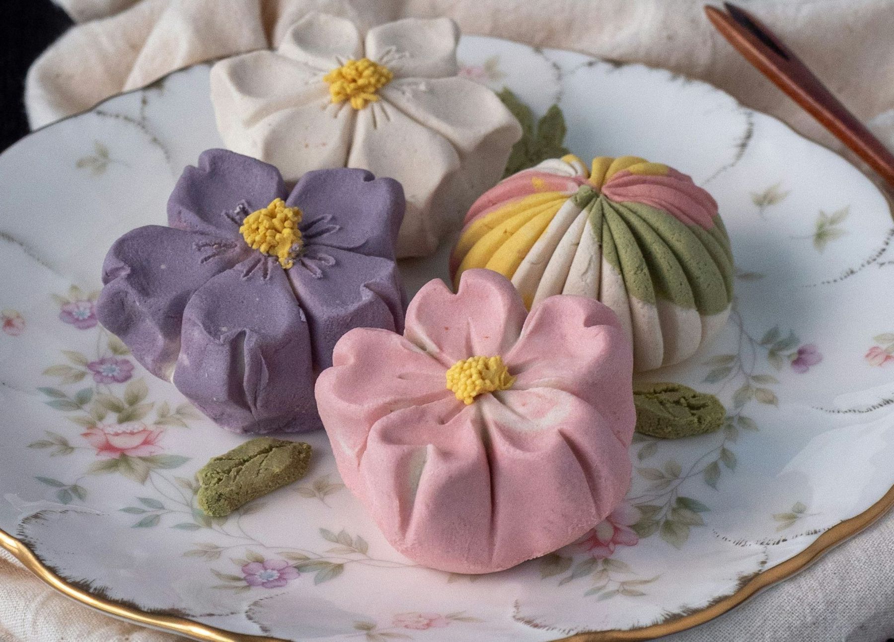 White and pink floral-shaped wagashi sweets on a floral ceramic plate