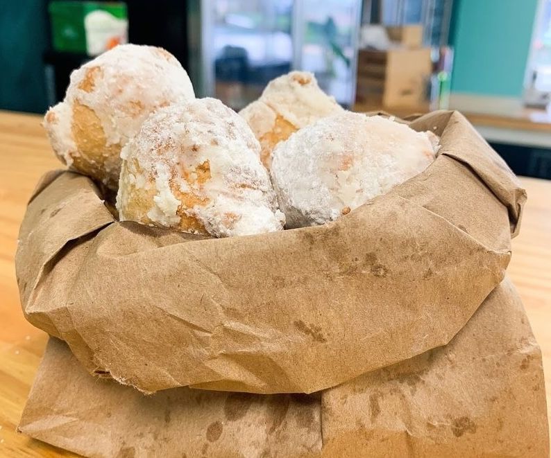 Jersey Shore zeppoles covered in powdered sugar and served in a brown paper bag